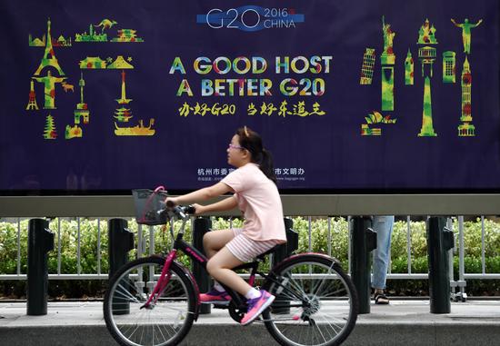8月27日，在杭州市西湖南山路，一個小朋友騎車從G20宣傳畫前經(jīng)過。 新華社記者 鞠煥宗 攝.jpg