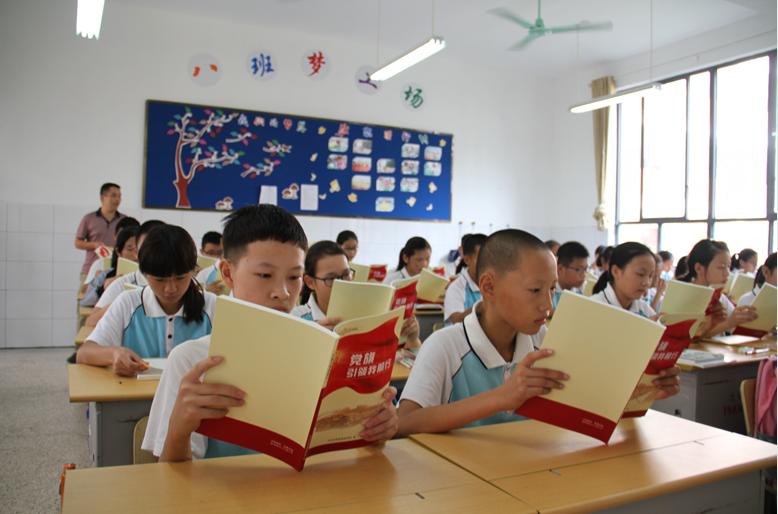 學(xué)生們集體學(xué)習(xí)《黨旗引領(lǐng)我前行》一書。.png